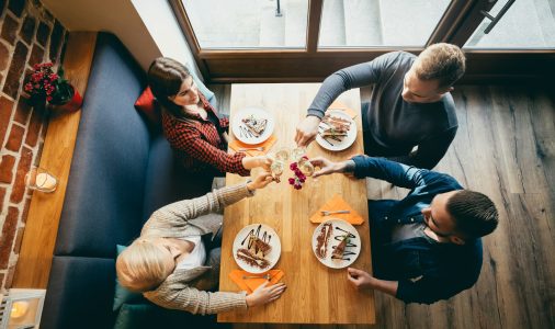 Four friends toasting in a restaurant. Top view.