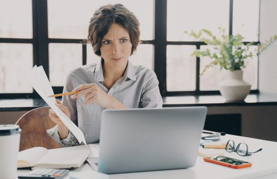 Serious focused Italian businesswoman making video call on laptop in office