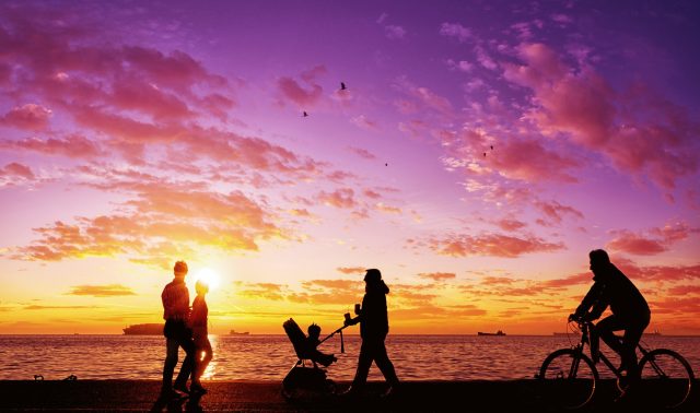 Silhouettes of people enjoying a walk by the seaside