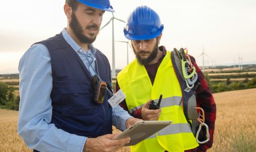 Two working men in a field of windmills. Renewable energies, engineers